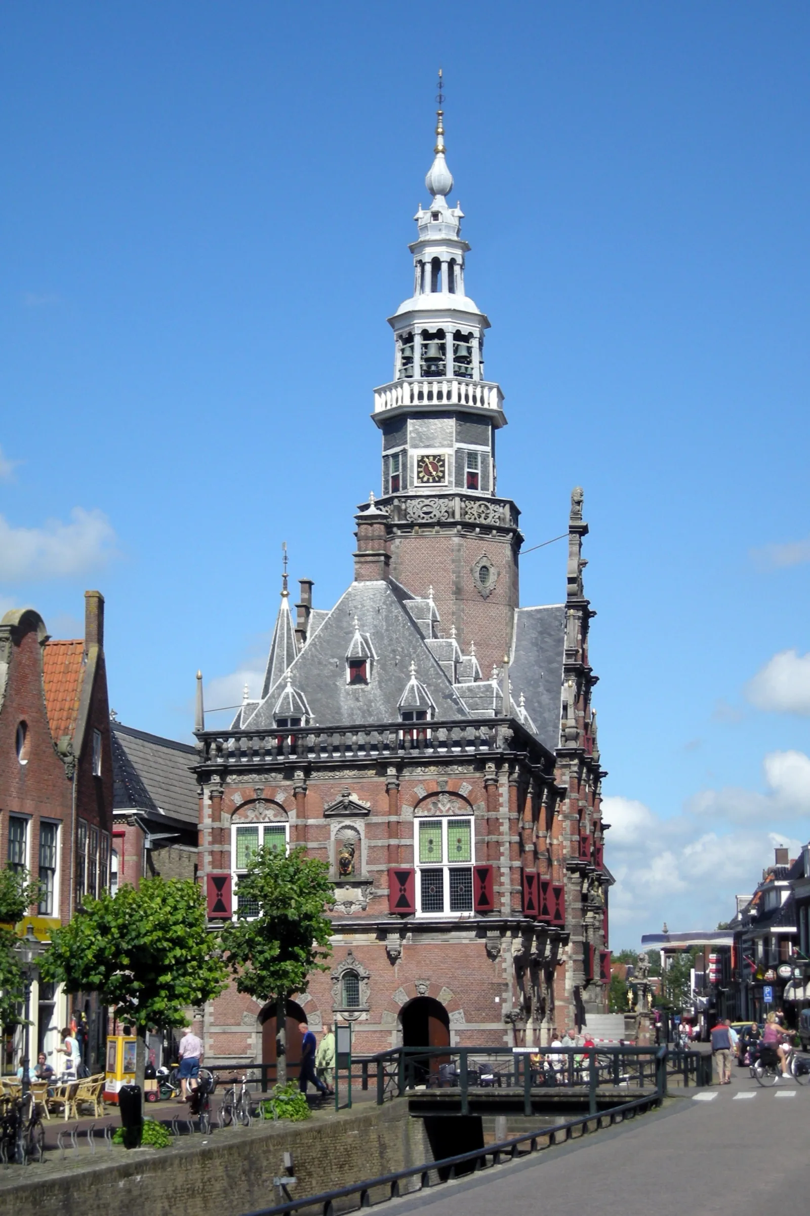 Het rijk versierde renaissance-stadhuis van Bolsward met sierlijke witte toren en trapgevel, onder een blauwe lucht