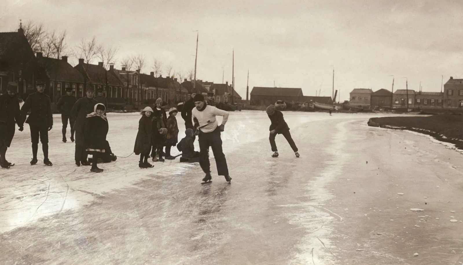 Deelnemers van de derde Elfstedentocht schaatsen door Stavoren op 27 januari 1917, met huizen aan de waterkant