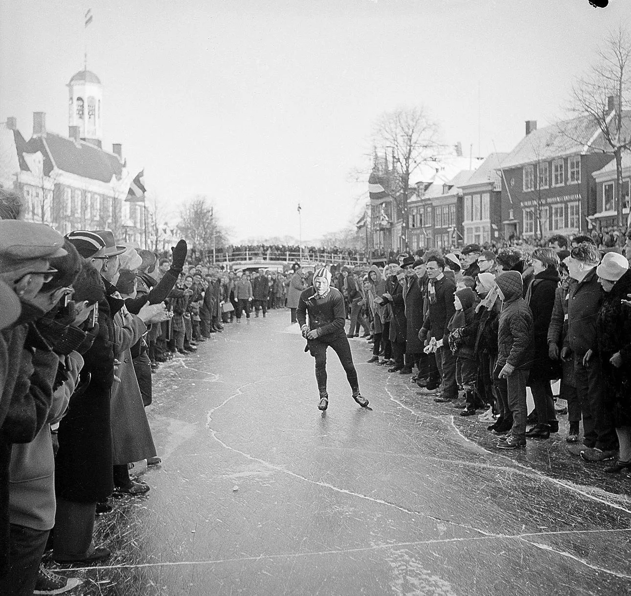 Reinier Paping schaatst alleen door een haag van toeschouwers in Dokkum tijdens de Elfstedentocht van 18 januari 1963