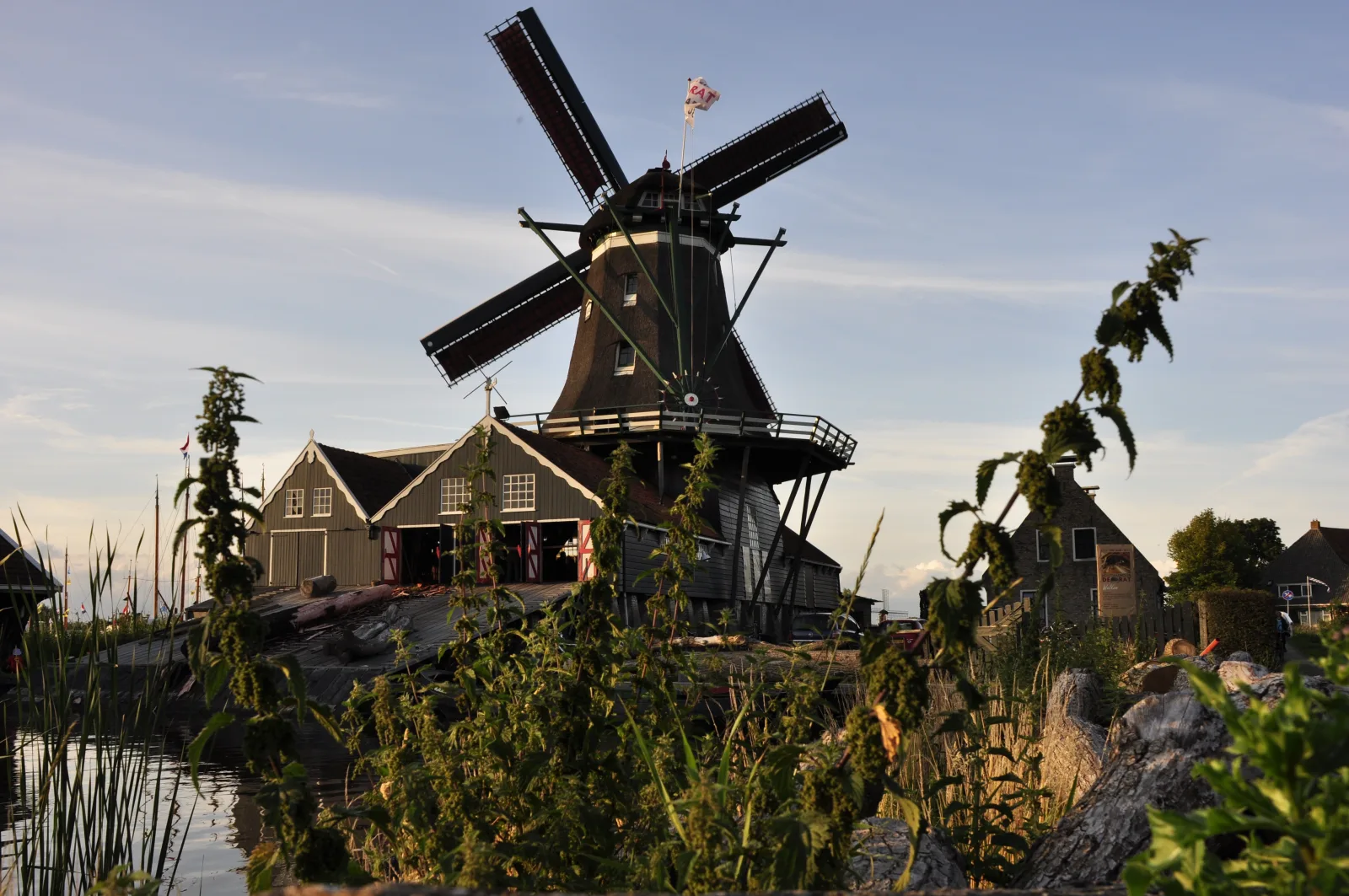 Houtzaagmolen De Rat in IJlst tijdens het gouden uur, met opgaande wieken en warme avondzon op het houten lijf