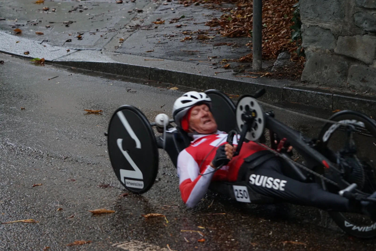 Handbiker met startnummer in race-positie op een natte weg tijdens UCI wereldkampioenschap parawielrennen