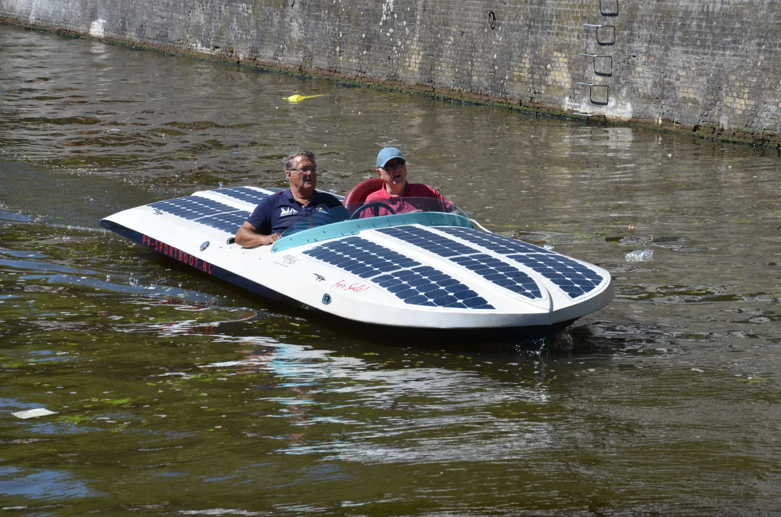 Twee mensen varen in een smalle zonneboot met zonnepanelen door een gracht in Leeuwarden